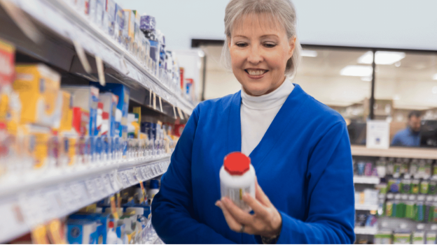 Woman comparing OTC pain relievers in a pharmacy