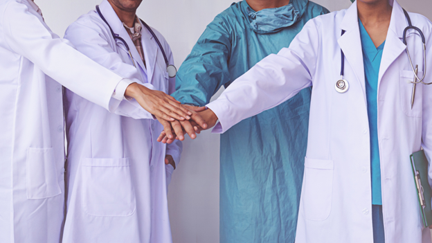 Village Medical coordinated care doctors stacking their hands